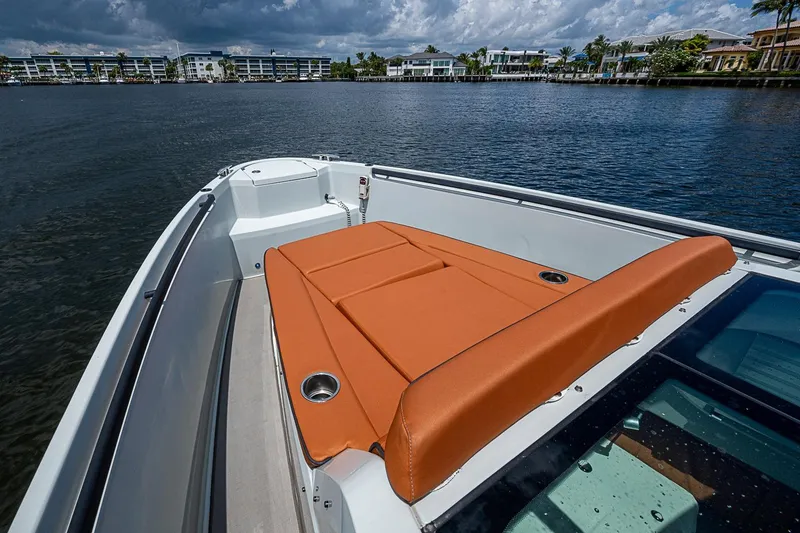Slide: The Image of 2023 Saxdor 320 GTO boat with orange seating, docked by waterfront homes under cloudy skies. - 7
