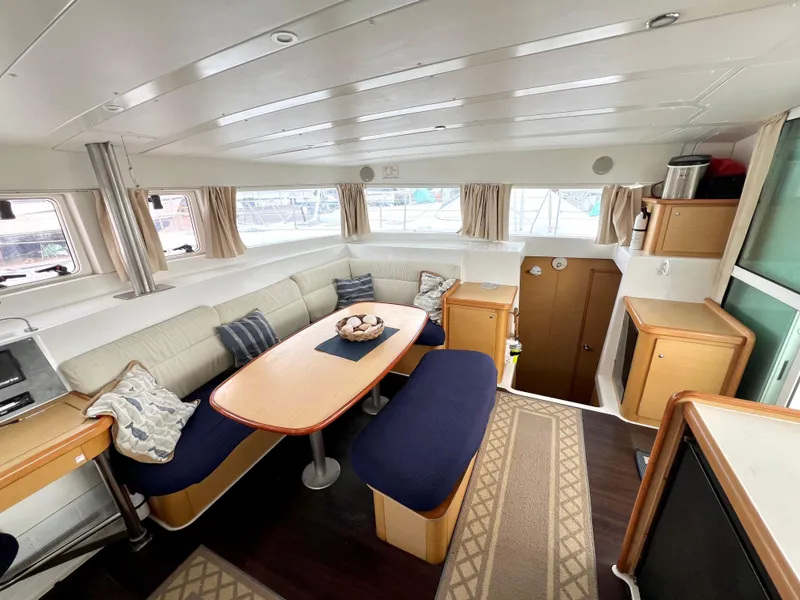 Slide: The Image of Interior of 2008 Lagoon 420 yacht, featuring a cozy dining area with blue seating. - 16