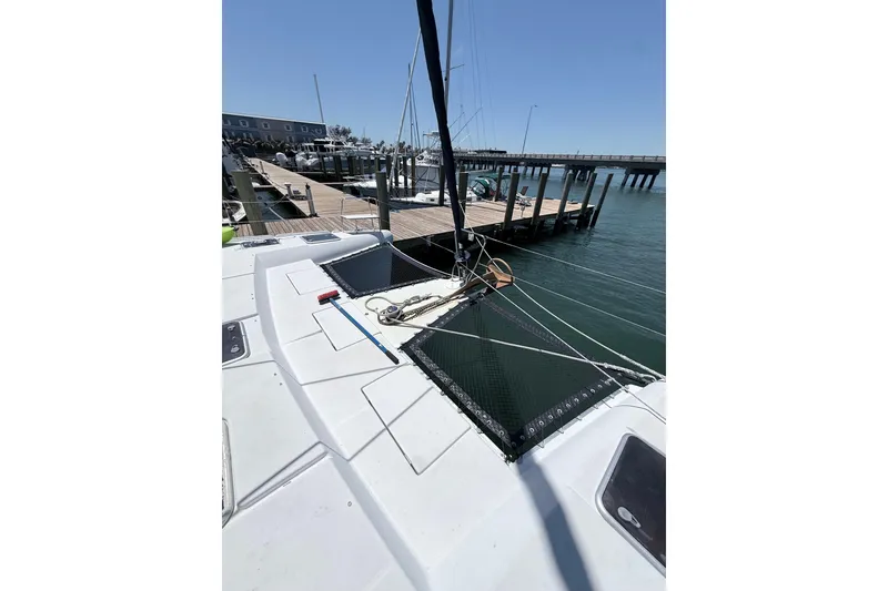 Slide: The Image of 2008 Lagoon 420 catamaran docked at a marina, featuring spacious deck and netting. - 32