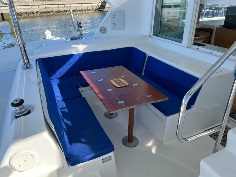 Slide: The Image of Lagoon 420 yacht cockpit with blue cushioned seating and wooden table, 2008 model. - 4