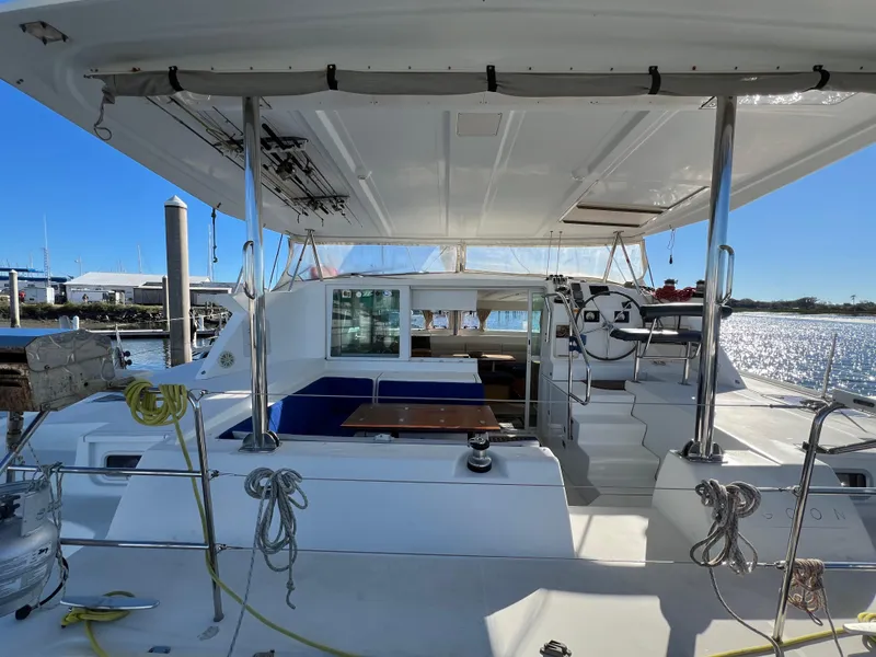 Slide: The Image of 2008 Lagoon 420 catamaran cockpit with seating, steering wheel, and marina view. - 7