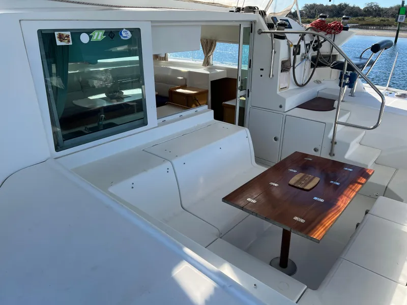 Slide: The Image of 2008 Lagoon 420 yacht cockpit with seating, table, and helm, overlooking water. - 8