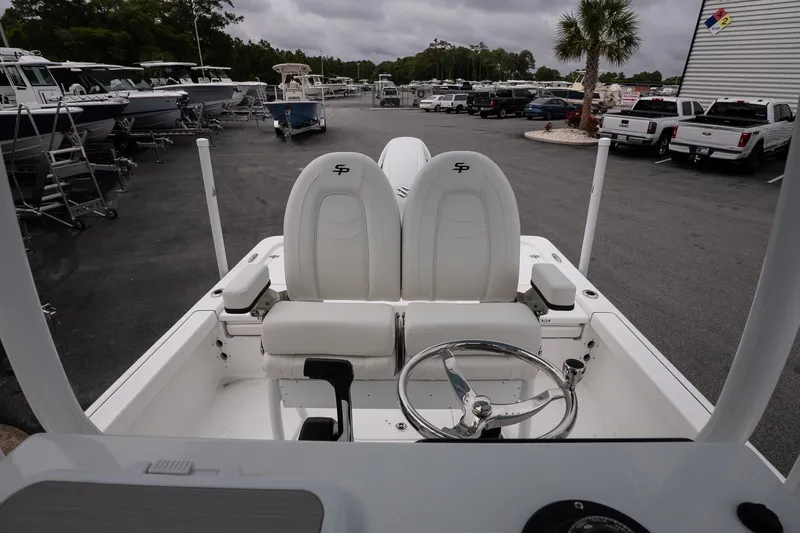 Slide: The Image of 2026 Sea Pro 230 Bay boat interior with dual seats and steering wheel in a marina setting. - 11