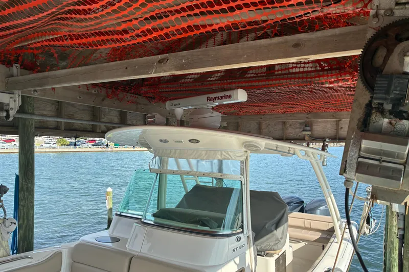 Slide: The Image of 2015 Pursuit ST 310 Sport boat docked under a wooden shelter. - 4