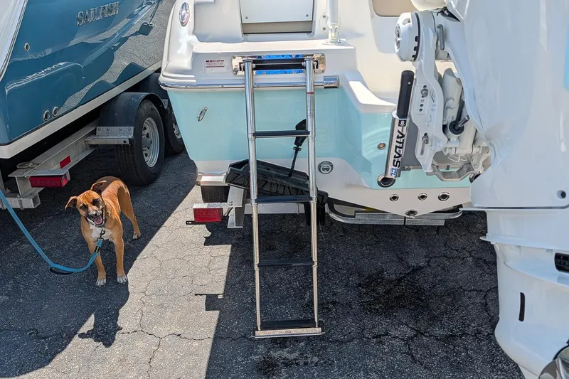 Slide: The Image of A 2026 Key West 249 FS boat with a ladder, parked beside a happy dog. - 8