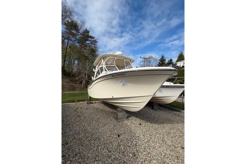 The Image of 2012 Grady-White Freedom 235 boat on gravel, under a blue sky. - 1