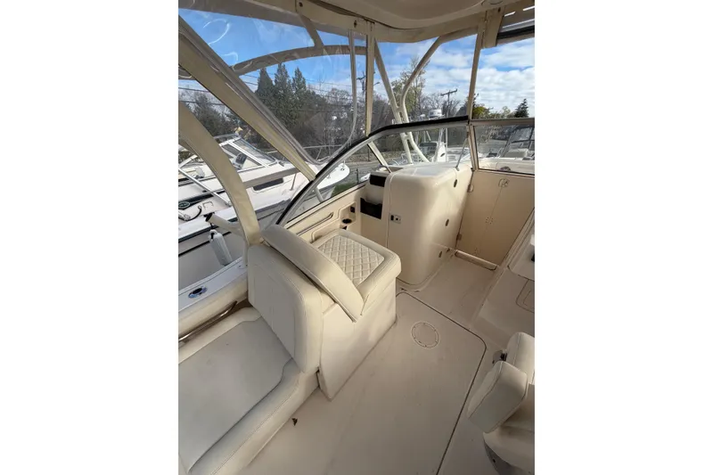 Slide: The Image of Interior of a 2012 Grady-White Freedom 235 boat, featuring beige seating and helm. - 6