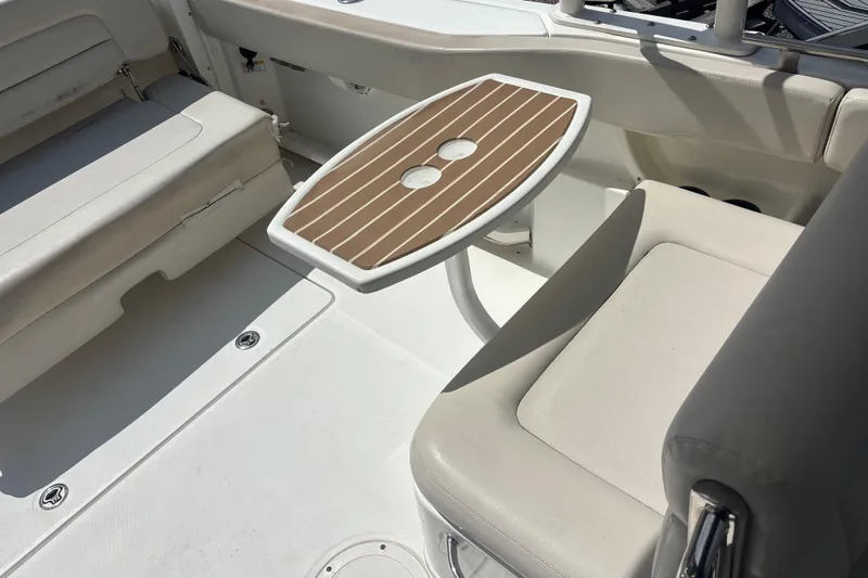 Slide: The Image of 2019 Boston Whaler 270 Vantage interior with cushioned seating and a small wooden table. - 10