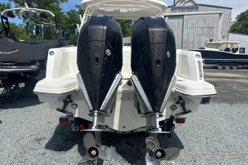 Slide: The Image of 2019 Boston Whaler 270 Vantage with dual outboard engines, parked on gravel. - 4