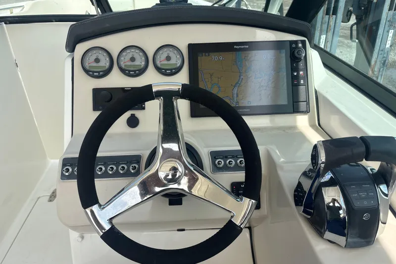 Slide: The Image of 2019 Boston Whaler 270 Vantage dashboard with steering wheel, gauges, and navigation display. - 8