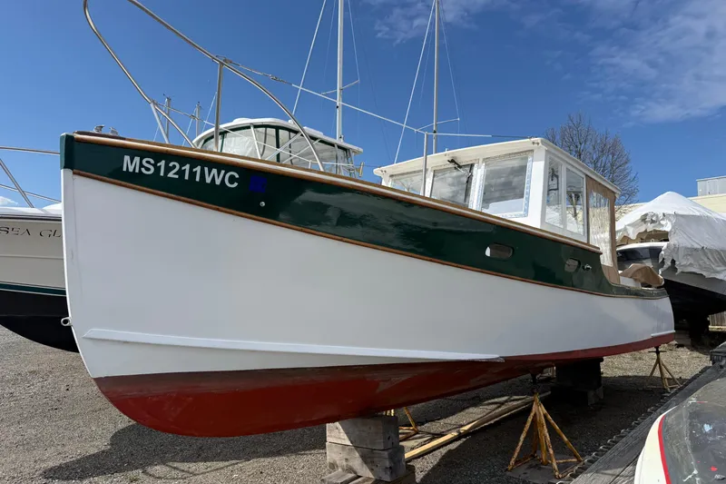Slide: The Image of 2024 Hylan Bowler boat on stands, green and white hull, clear sky background. - 11