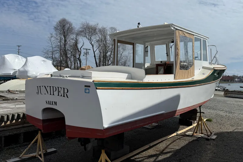 Slide: The Image of 2024 Hylan Bowler boat named "Juniper" on stands, dockside setting. - 12