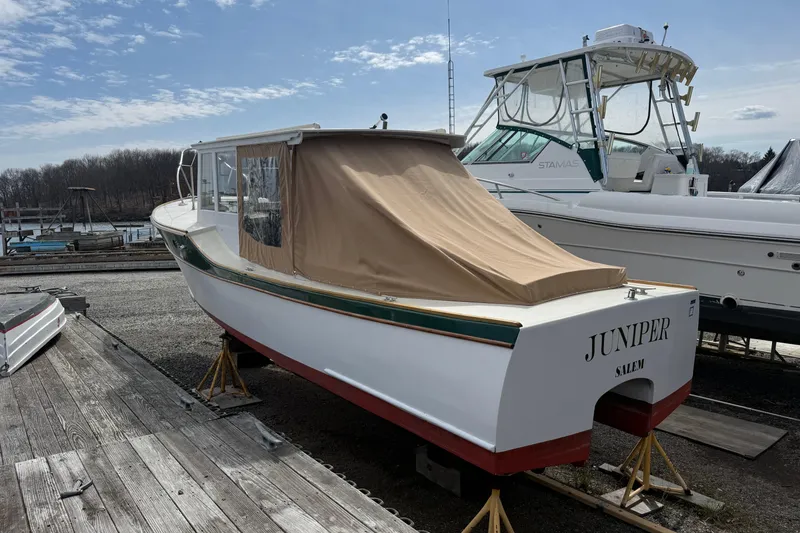 Slide: The Image of 2024 Hylan Bowler boat named "Juniper" on dry dock, with beige cover. - 13