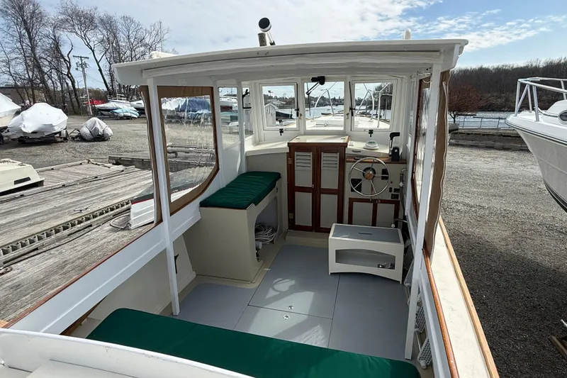 Slide: The Image of 2024 Hylan Bowler boat interior with green seating, steering wheel, and docked surroundings. - 16