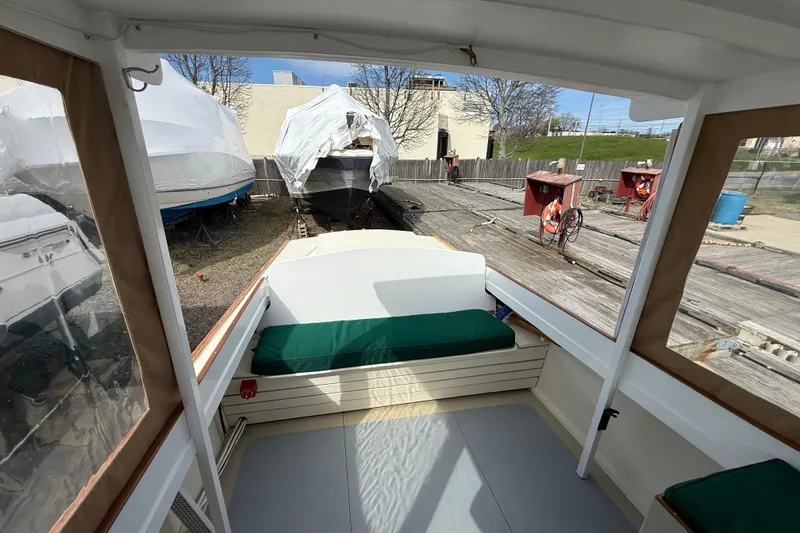 Slide: The Image of 2024 Hylan Bowler boat interior with green cushions, docked near covered boats. - 21