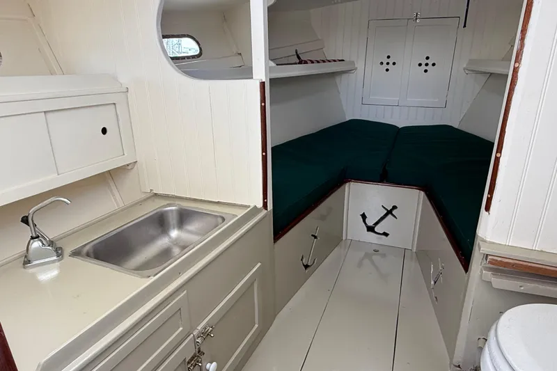 Slide: The Image of 2024 Hylan Bowler boat interior with kitchenette, sink, and cozy sleeping area. - 26