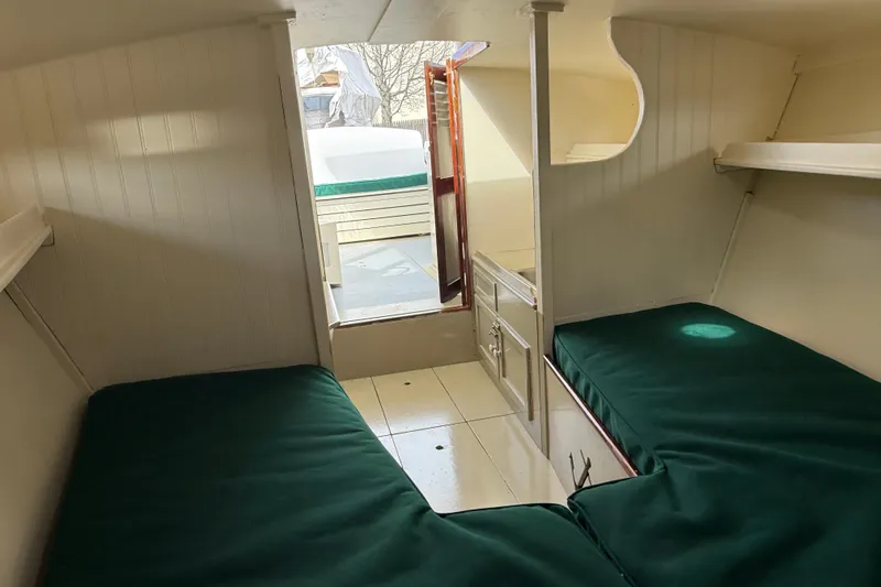 Slide: The Image of Interior of 2024 Hylan Bowler boat with green-cushioned bunks and wooden cabinetry. - 30