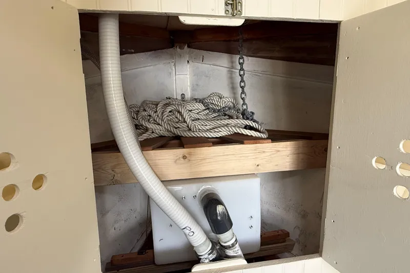 Slide: The Image of Storage compartment in a 2024 Hylan Bowler boat, featuring ropes and ventilation pipes. - 42