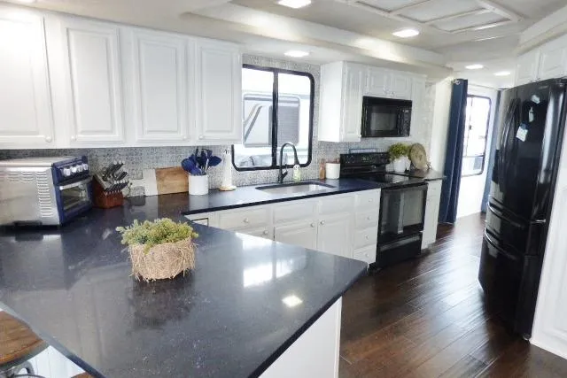 Slide: The Image of Modern kitchen in a 1997 Sumerset 16x80 houseboat with sleek black countertops. - 4