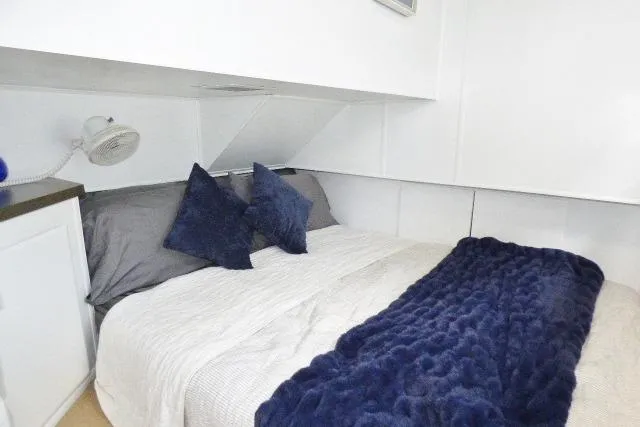 Slide: The Image of Cozy bedroom in a 1997 Sumerset 16x80 houseboat with plush navy bedding. - 7