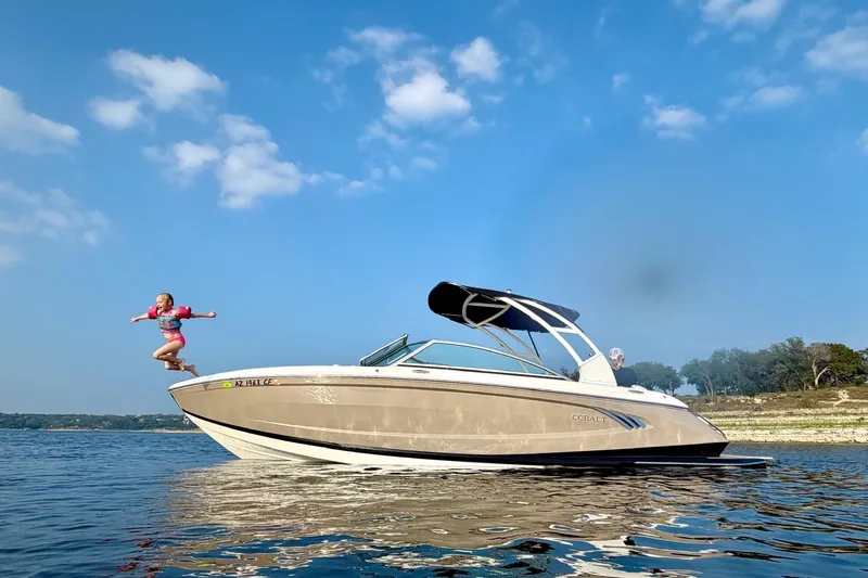 The Image of Child jumping off a 2013 Cobalt A25 boat on a sunny day. - 1