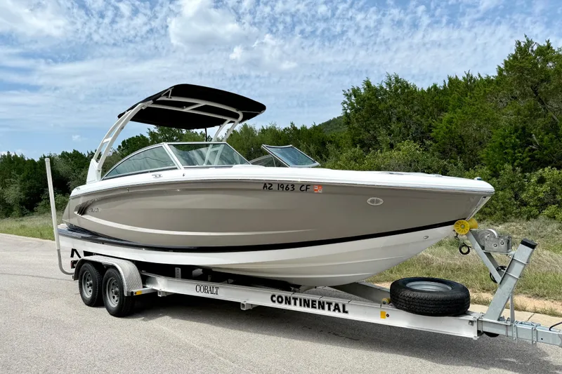 Slide: The Image of 2013 Cobalt A25 boat on trailer, parked on roadside with trees in background. - 12