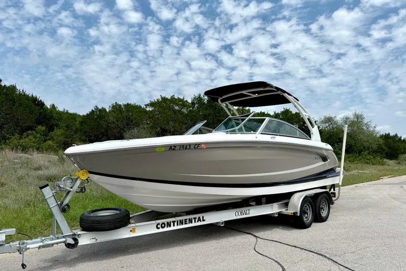 Slide: The Image of 2013 Cobalt A25 boat on trailer, parked on roadside under cloudy sky. - 16