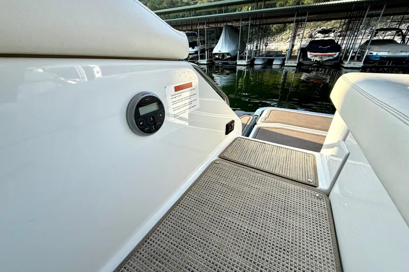 Slide: The Image of 2013 Cobalt A25 boat interior with seating and control panel, docked near other boats. - 35
