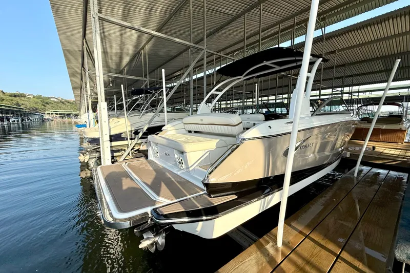 Slide: The Image of 2013 Cobalt A25 boat docked under a covered marina, showcasing sleek design and luxury features. - 37