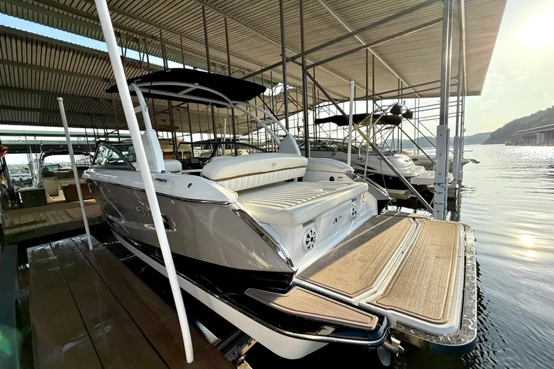 Slide: The Image of 2013 Cobalt A25 boat docked under a covered marina, with scenic water view. - 40