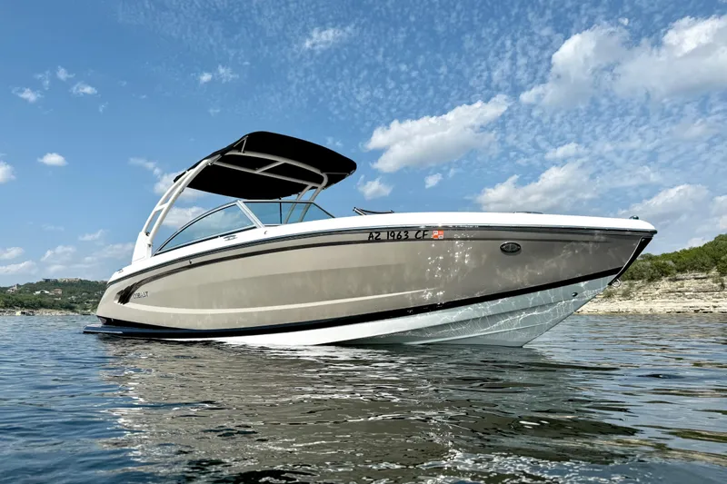Slide: The Image of 2013 Cobalt A25 boat cruising on a lake under a partly cloudy sky. - 5