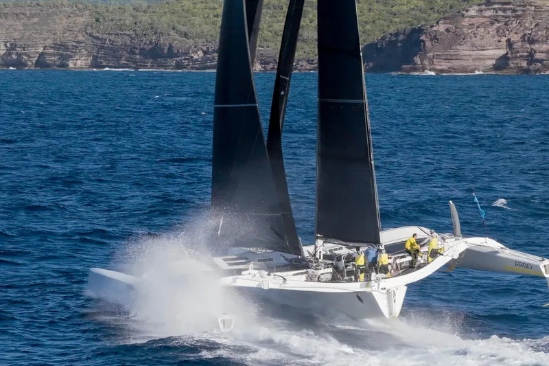 Slide: The Image of Sailing yacht CDK Technologies MOD 70, 2012 model, navigating ocean waves near rocky coastline. - 63