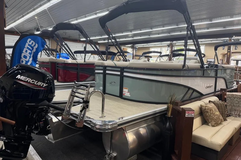 Slide: The Image of 2026 Crest Conquest 230 SLC pontoon boat displayed indoors with Mercury engine. - 16