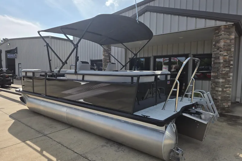 Slide: The Image of 2026 Dockside 22DQ2.75 pontoon boat with canopy, parked outside a service building. - 3