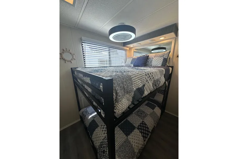 Slide: The Image of Bunk beds in a 1995 Lakeview 15x70 houseboat, featuring patterned bedding and modern lighting. - 2