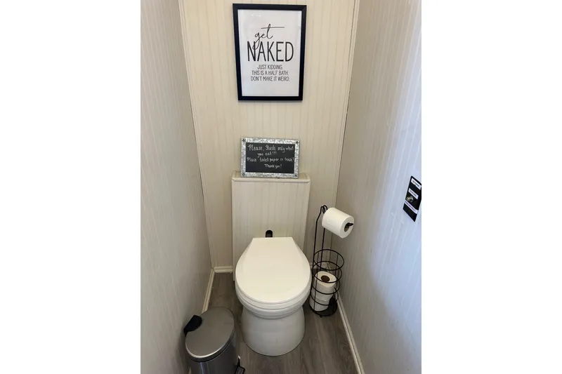 Slide: The Image of Compact bathroom in a 1995 Lakeview 15x70, featuring humorous wall art and modern decor. - 3
