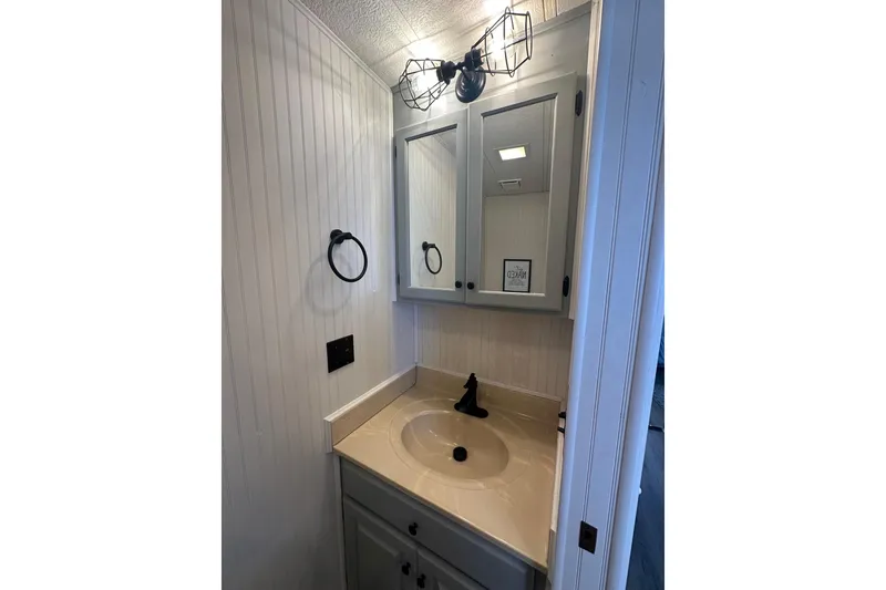 Slide: The Image of Compact bathroom vanity with mirror, modern lighting, and beige countertop in 1995 Lakeview model. - 4