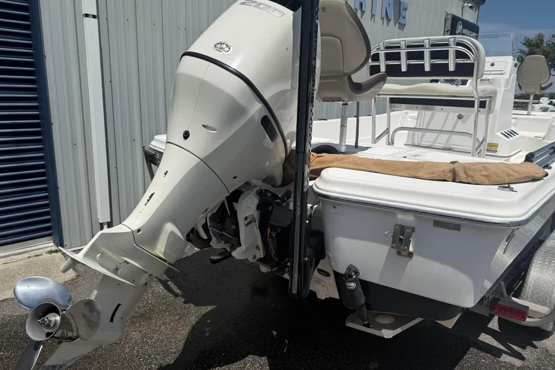 Slide: The Image of 2019 Aquasport 224 Bay boat with powerful outboard motor, docked near metal building. - 4