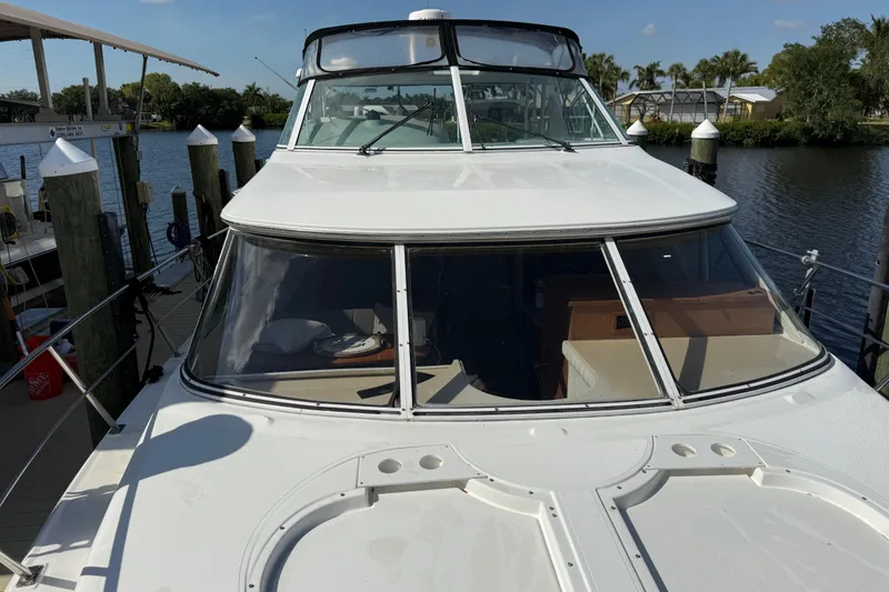 Slide: The Image of 2002 Cruisers Yachts 4450 Express Motoryacht docked by a serene waterfront. - 10
