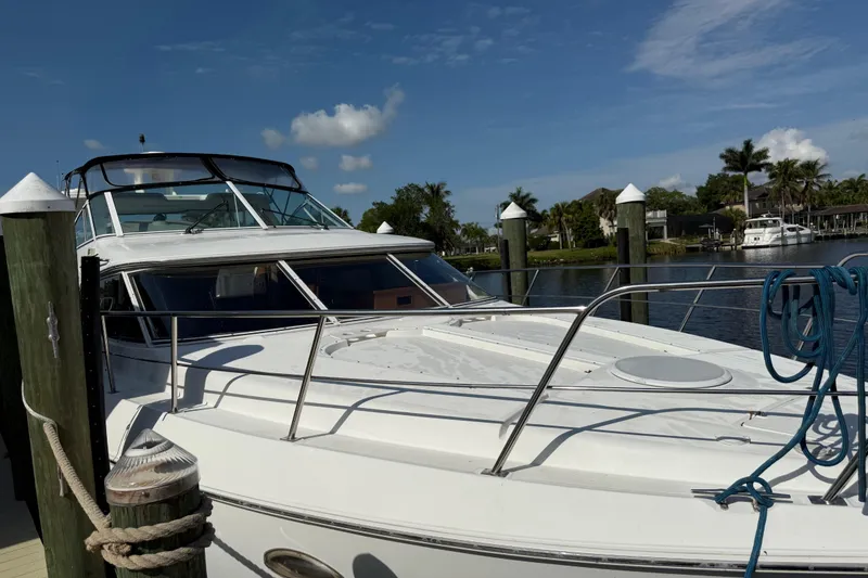 Slide: The Image of 2002 Cruisers Yachts 4450 Express Motoryacht docked by a serene waterfront. - 2
