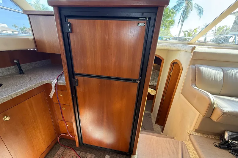 Slide: The Image of 2002 Cruisers Yachts 4450 Express Motoryacht interior with wooden cabinetry and refrigerator. - 60