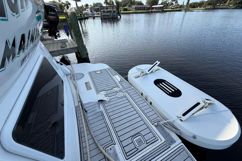 Slide: The Image of 2002 Cruisers Yachts 4450 Express Motoryacht docked with inflatable boat on calm water. - 76