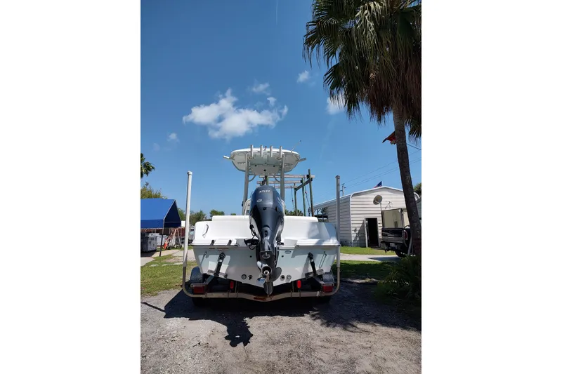 Slide: The Image of 2020 Sportsman Heritage 211 Center Console boat, rear view, parked outdoors under clear blue sky. - 11