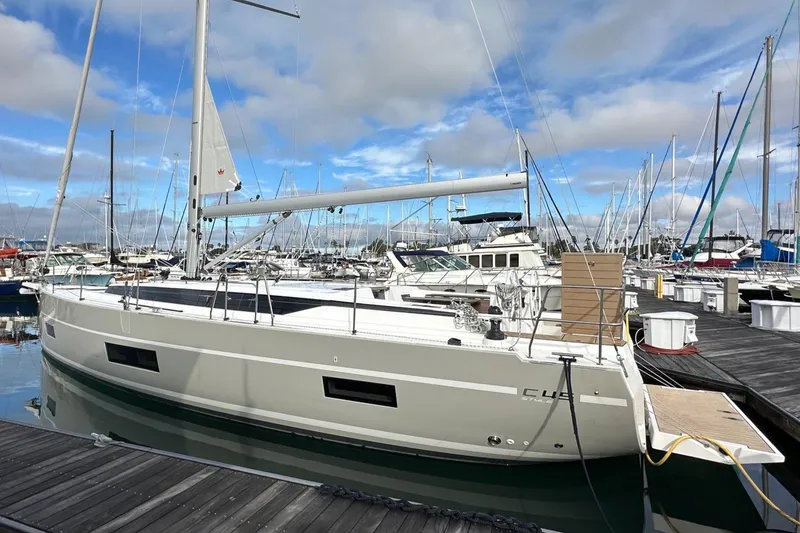 Slide: The Image of 2024 Bavaria C45 sailboat docked at a marina under a partly cloudy sky. - 0