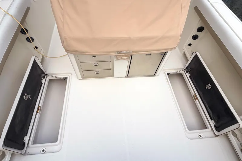 Slide: The Image of 2016 Sailfish 290 CC boat interior with storage compartments and beige cover. - 14