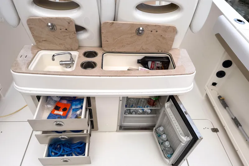 Slide: The Image of 2016 Sailfish 290 CC boat galley with sink, storage drawers, and mini fridge. - 16