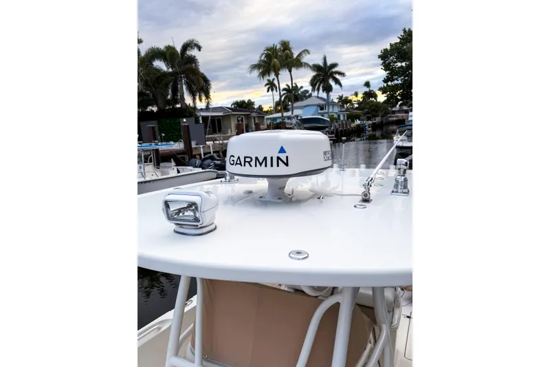 Slide: The Image of 2016 Sailfish 290 CC boat with Garmin radar, docked near palm trees. - 2