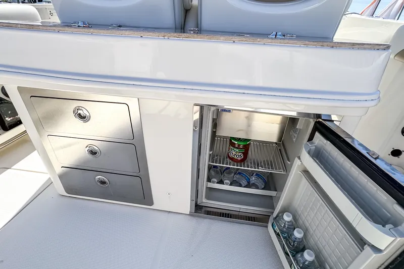 Slide: The Image of 2016 Sailfish 290 CC boat interior with storage drawers and open mini fridge. - 30