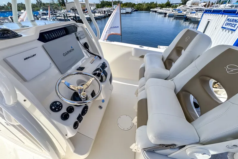 Slide: The Image of 2016 Sailfish 290 CC boat cockpit with Garmin navigation and dual seating at marina. - 33