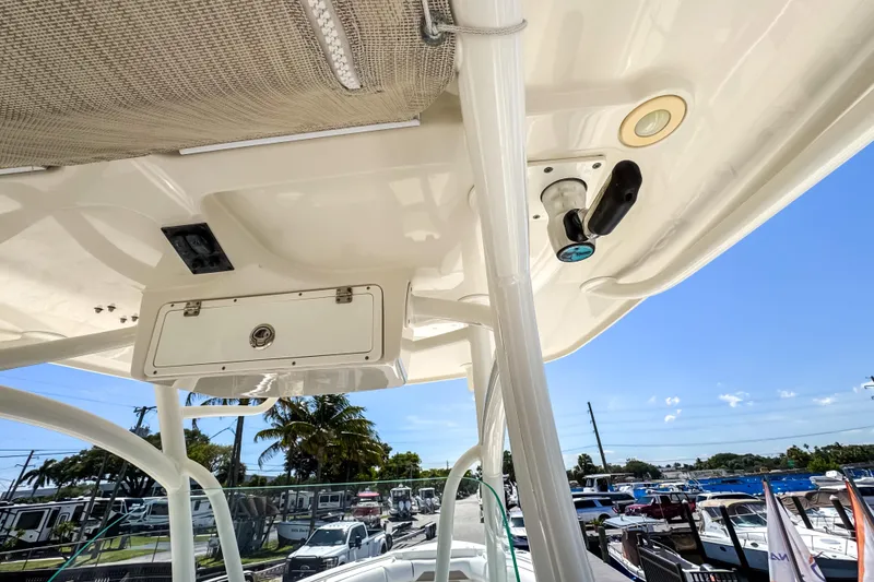 Slide: The Image of 2016 Sailfish 290 CC boat interior, featuring storage compartment and rod holder, with marina view. - 48